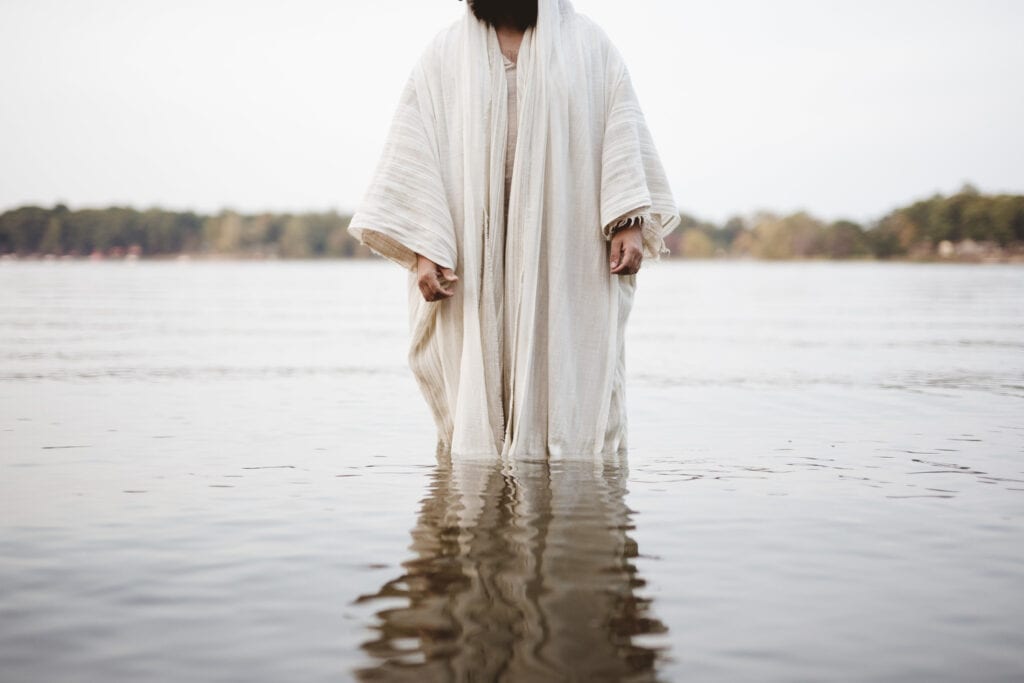 Jesus standing in the water before he's baptized symbolizing his commitment to his God-given identity
