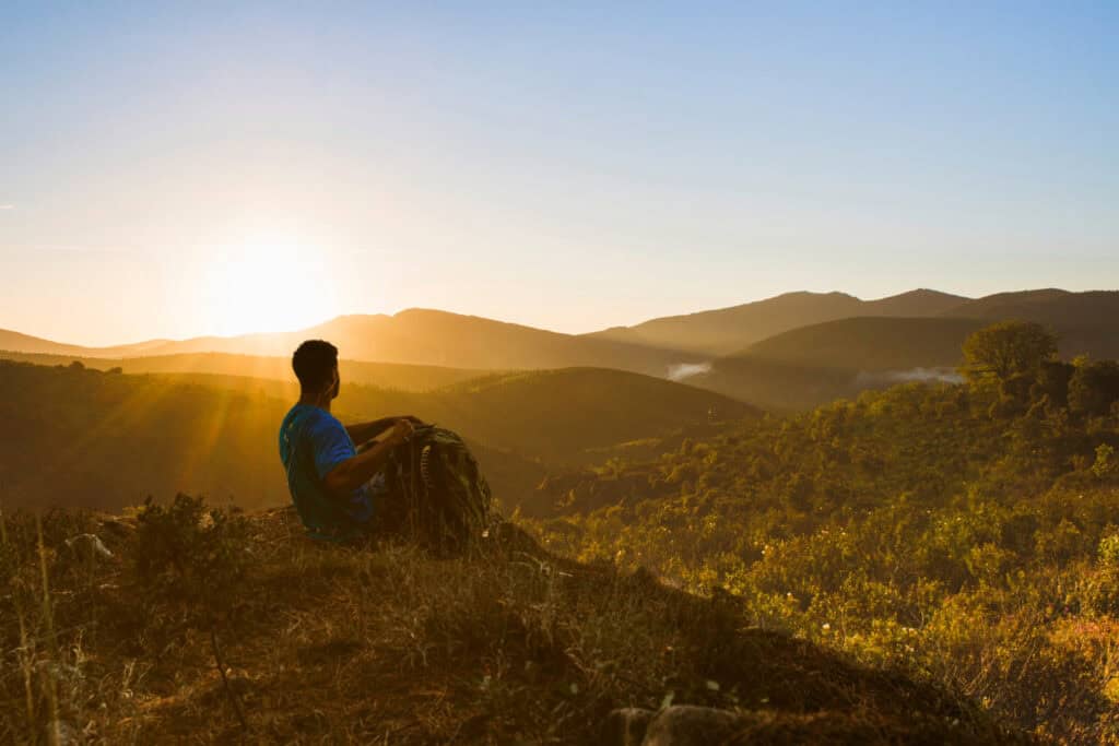 a man at the top of a mountain with a sunset symbolizing spiritual freedom and enlightenment