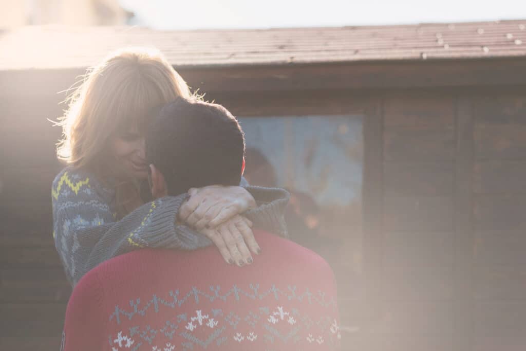  Two people embracing in natural light, expressing forgiveness and emotional healing born from the safety of divine rest.