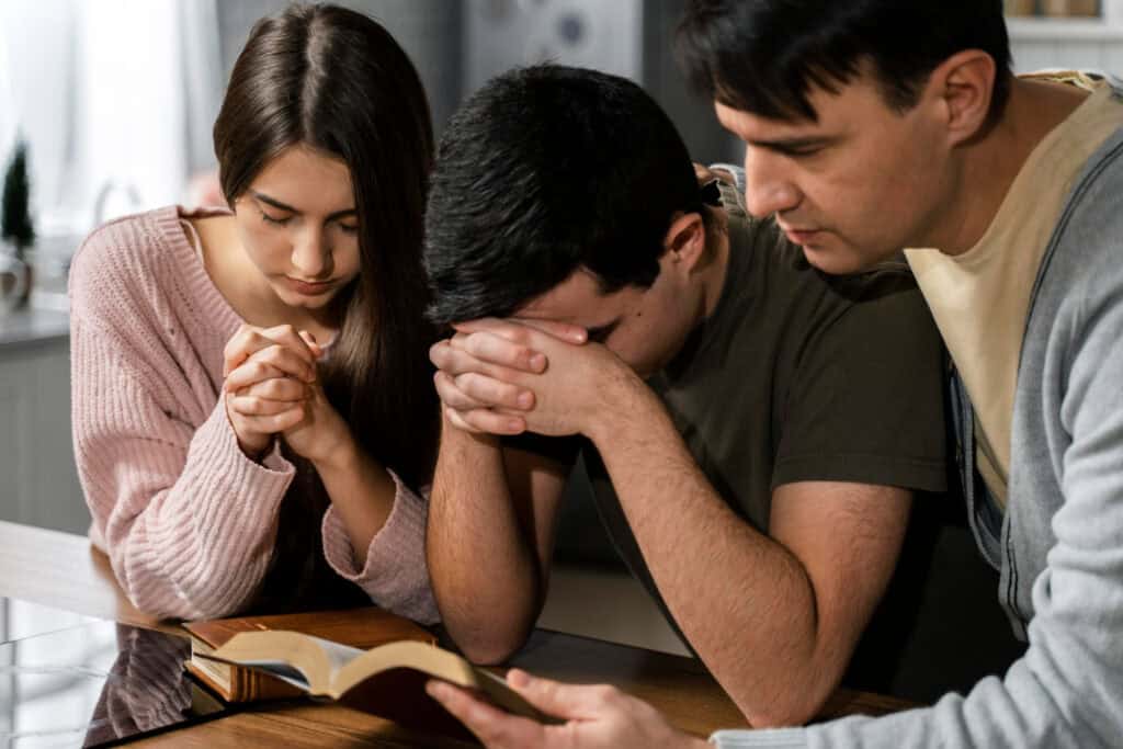 a family praying together symbolizing their trust in God to form godly relationships in their life