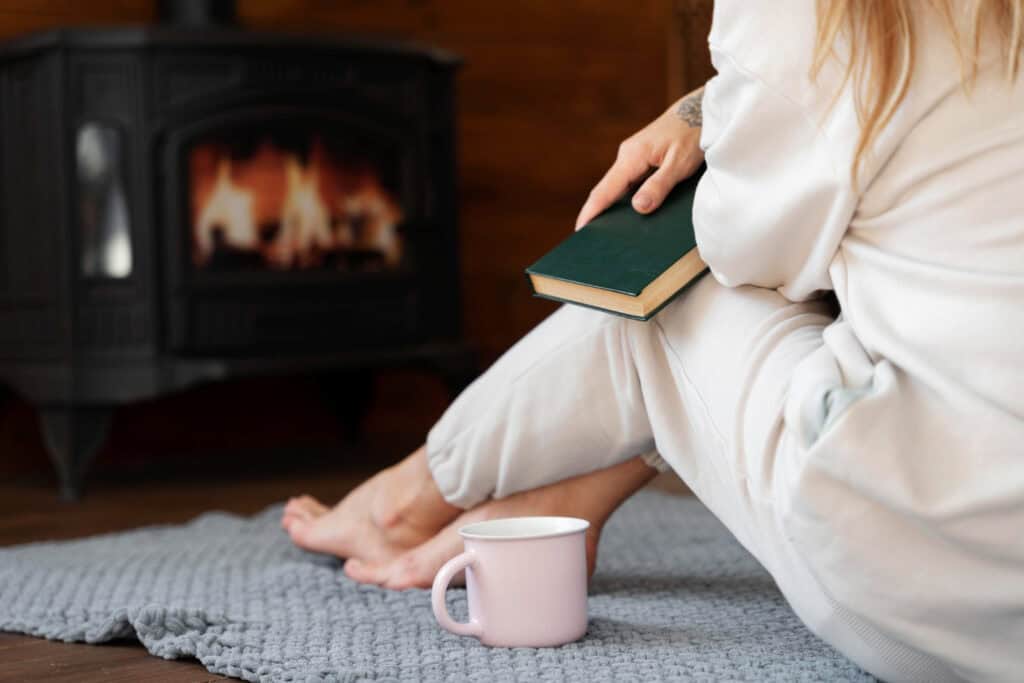 a young woman with her bible sitting by a fire praying