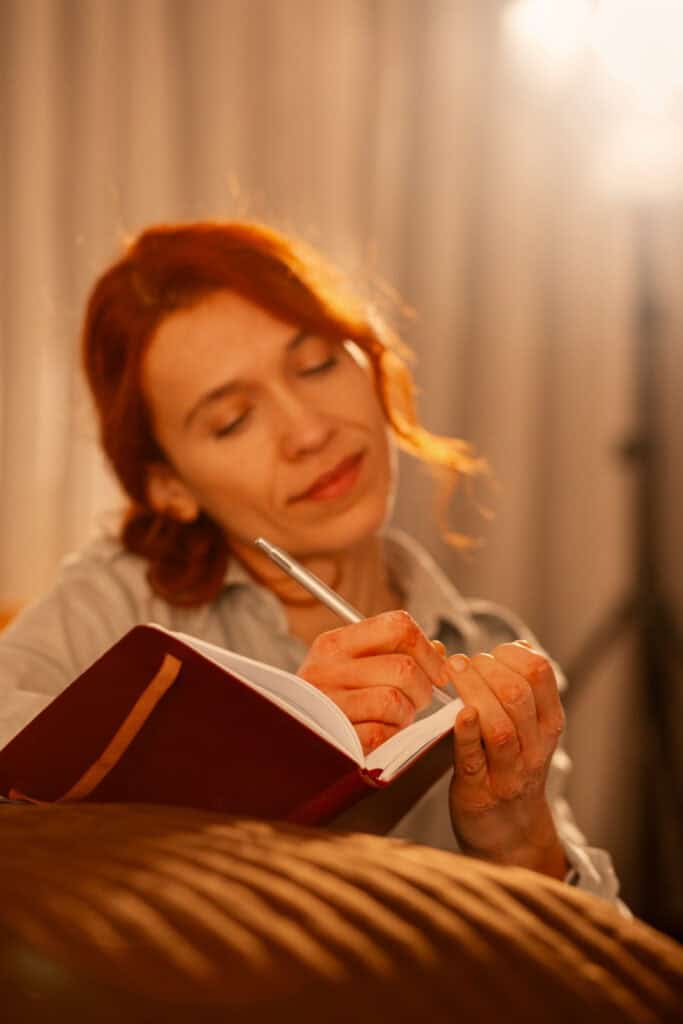 a woman writing in her journal with a warm glow from a light above her symbolizing her relationship with God