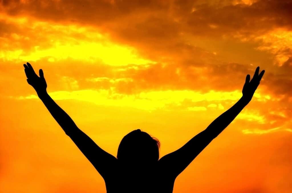 Outstretched hands lifted toward sunlight in surrender, receiving God’s love and stepping into a lifestyle of spiritual rest.