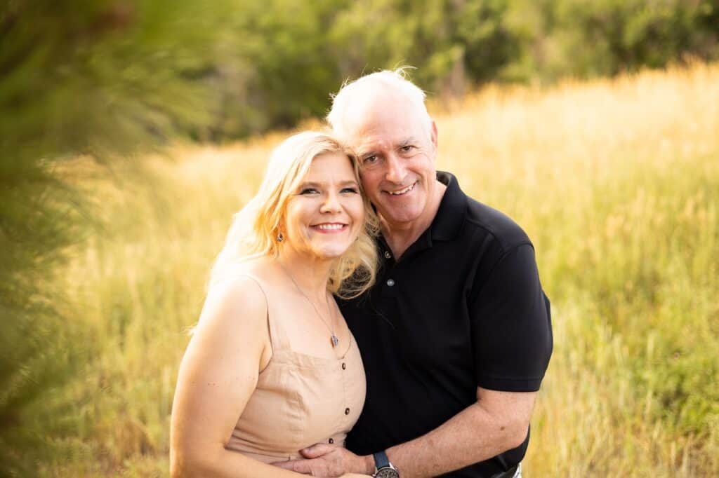 Catherine and Brian embracing in a field of golden grass