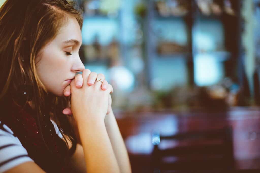 woman praying symbolizing reconnecting with God as the person of love who heals trauma