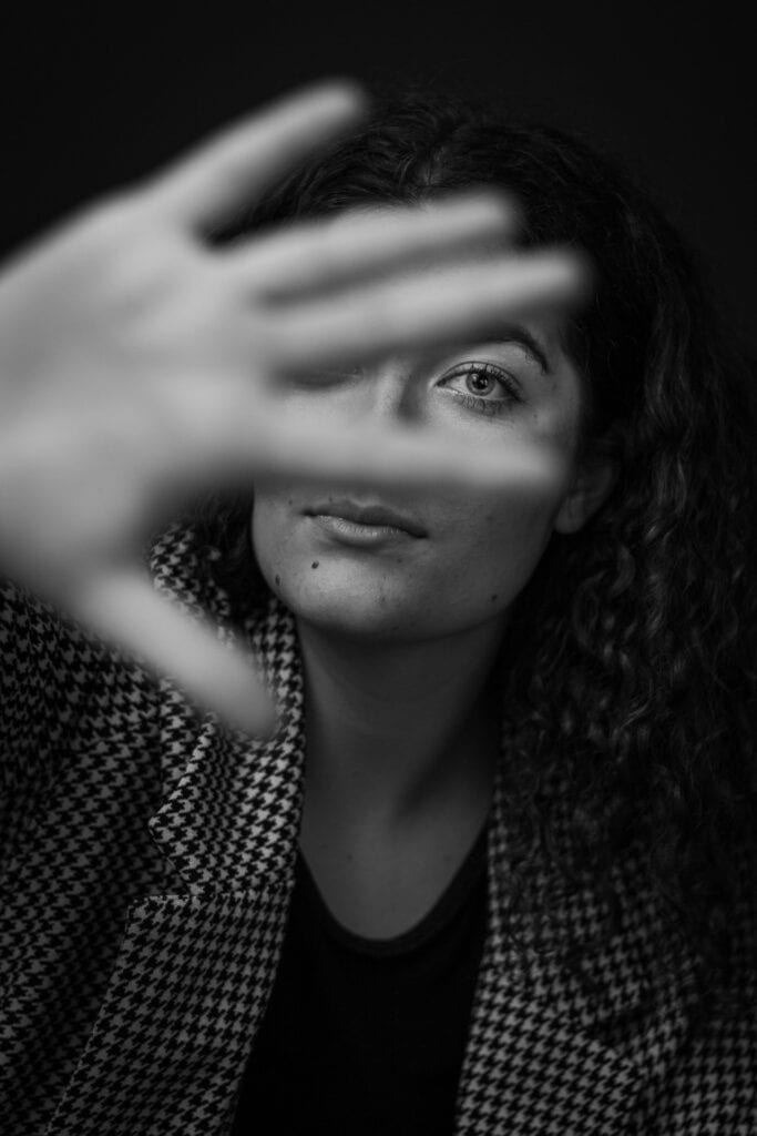 woman hiding her face with her hand from the camera symbolizing shame from trauma